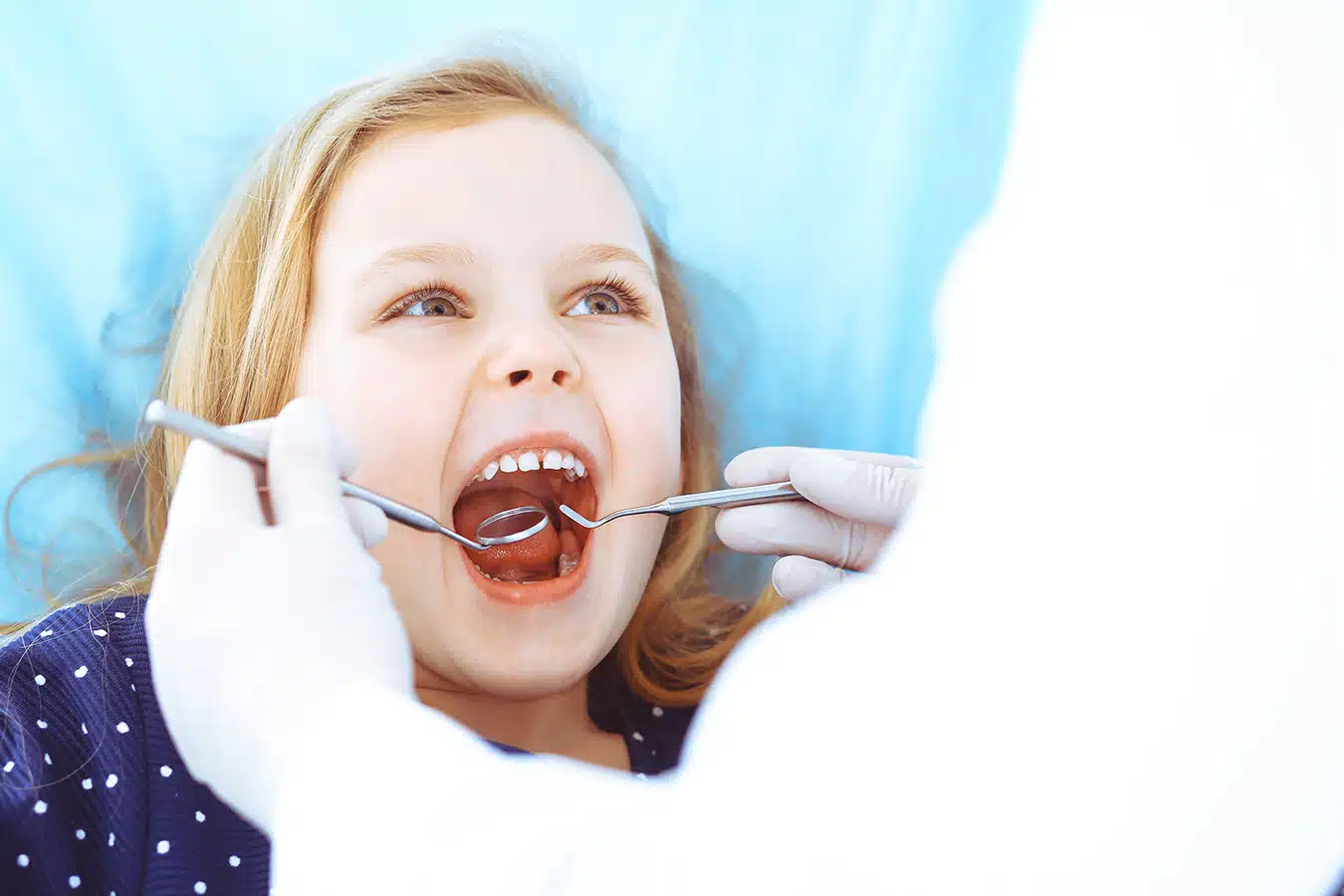 Little Baby Girl Sitting At Dental Chair With Open Mouth During