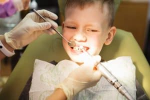 School-aged boy having his teeth checked by a dentist