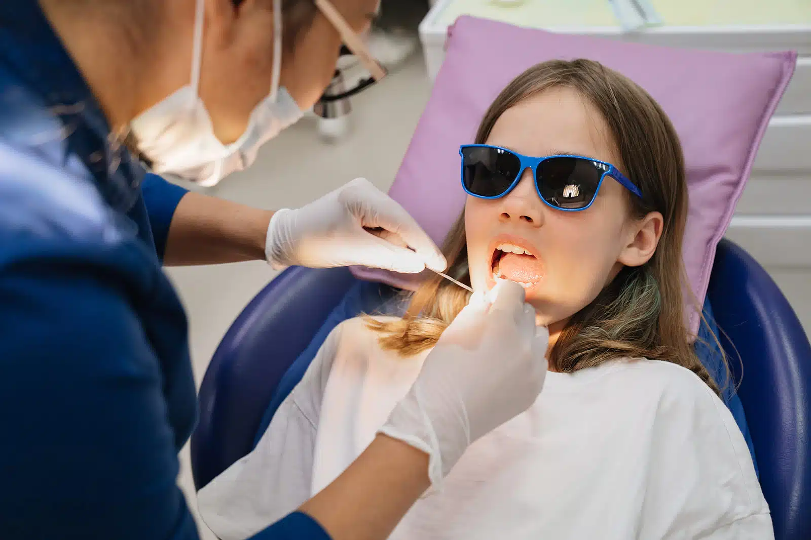 Dentist examining and flossing a teenager’s teeth