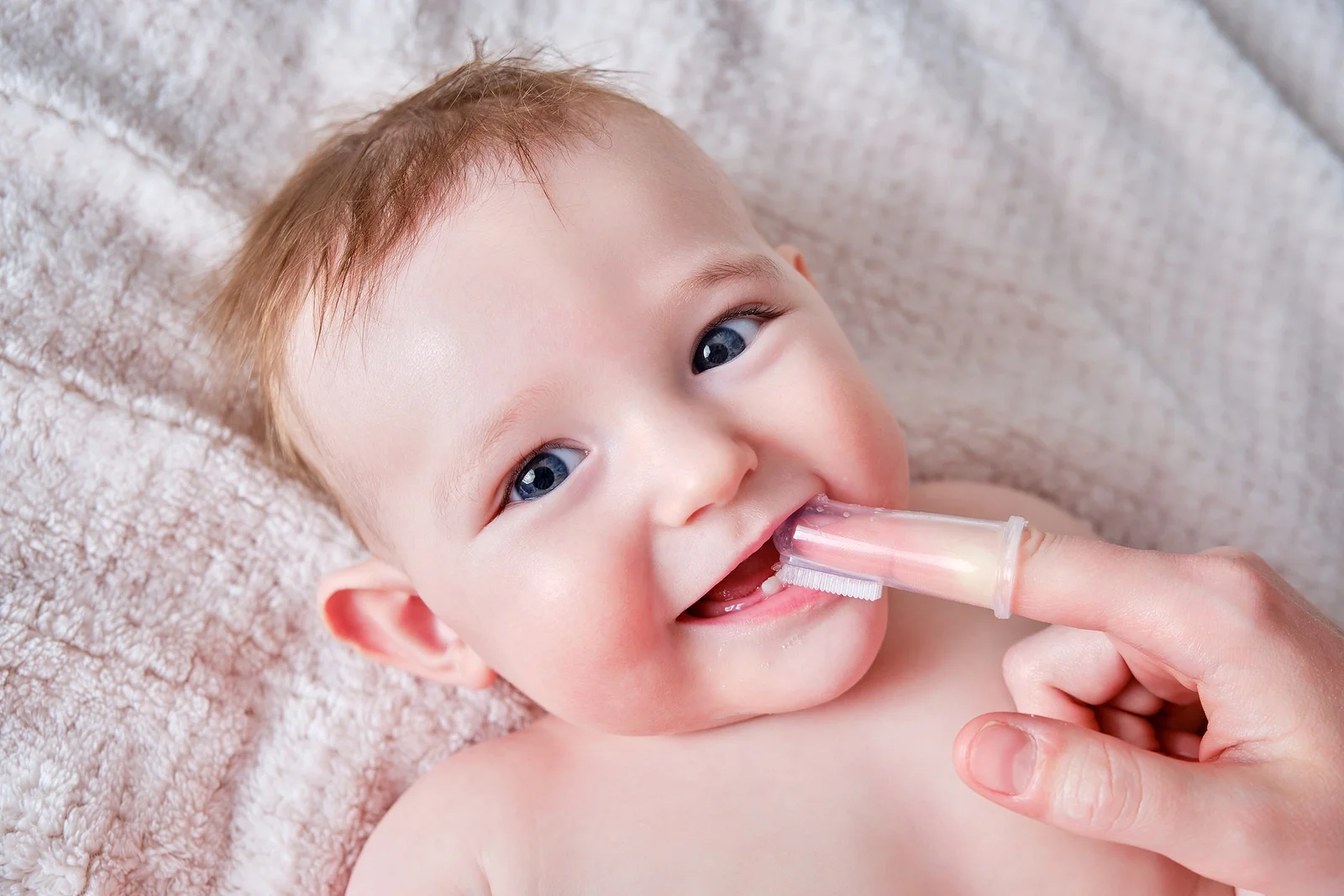 a mom cleaning a little baby's teeth